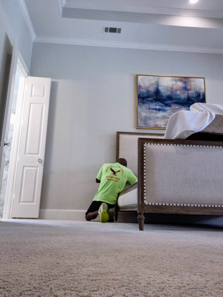Mover disassembling bedroom furniture including bed frame and dresser during a residential move